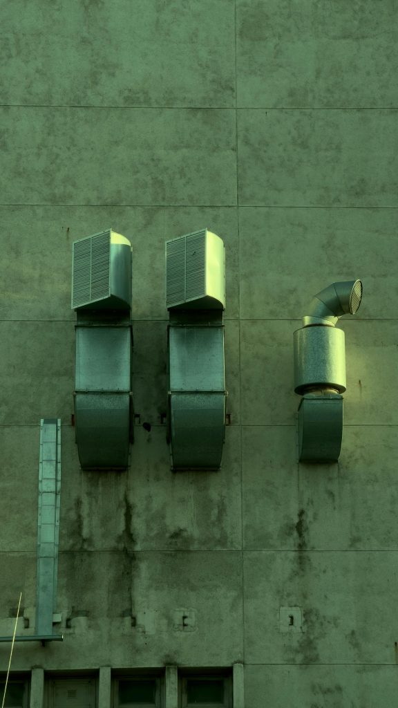 Close-up of industrial ventilation ducts on a city building wall.