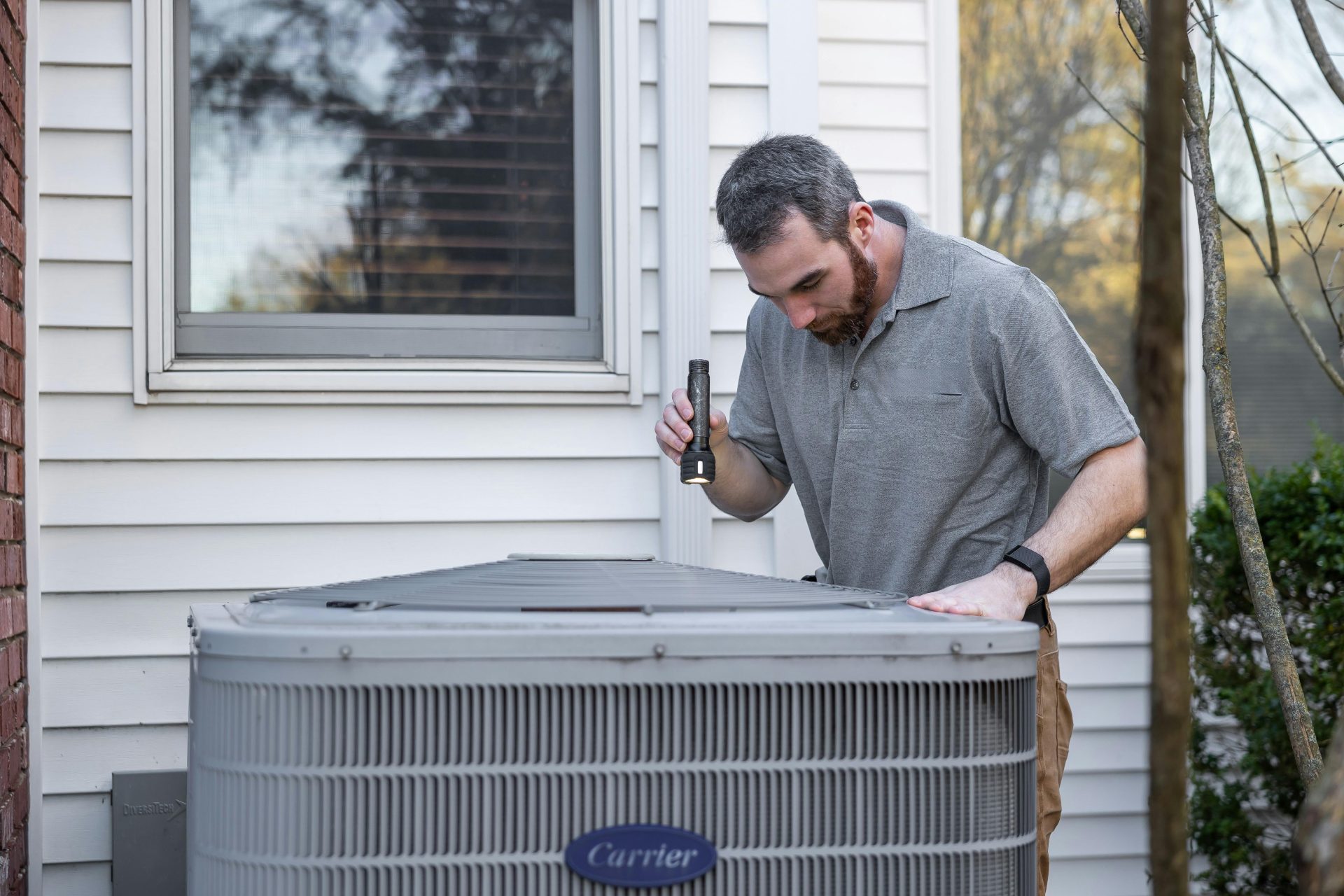 Un technicien inspecte une unité de climatisation extérieure en vue de son entretien.