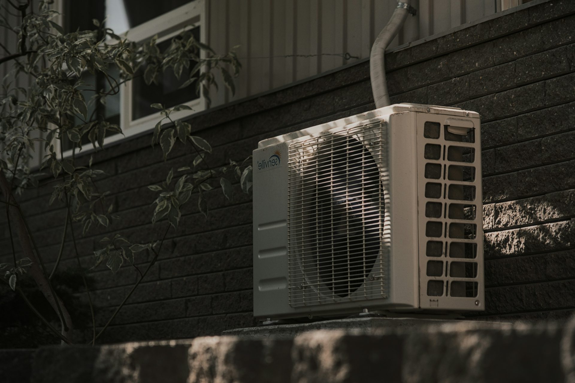 un climatiseur blanc posé sur un mur de briques
